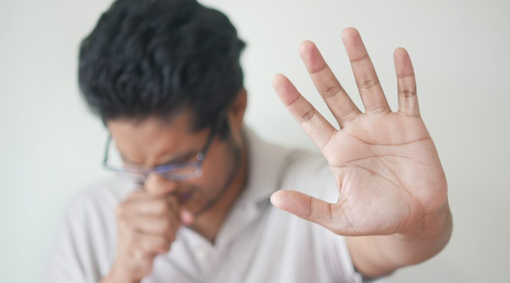 a man coughing with his hand out